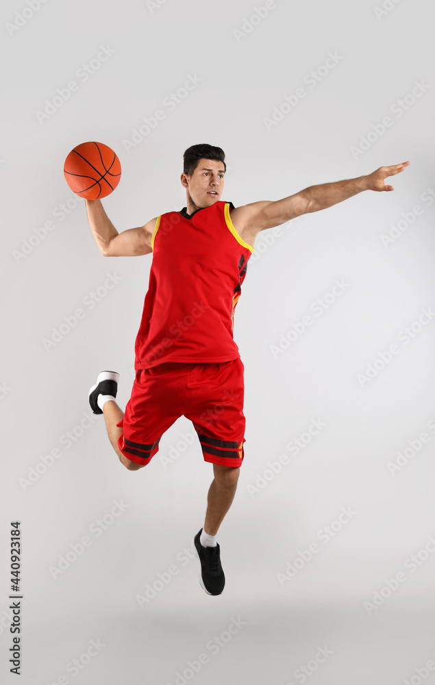 Poster Professional sportsman playing basketball on grey background