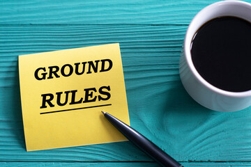 GROUND RULES - words on a yellow piece of paper on a green wooden background with a cup of coffee and a pen