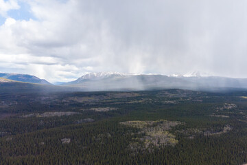 Northern boreal forest with heavy rain falling on the vast, wilderness landscape below. Taken...