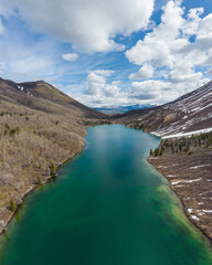 St Elias Lake. Portrait view of a stunning northern Canadian view in Yukon Territory during spring time with turquoise, emerald green lake surrounded by towering mountains and blue sky. 