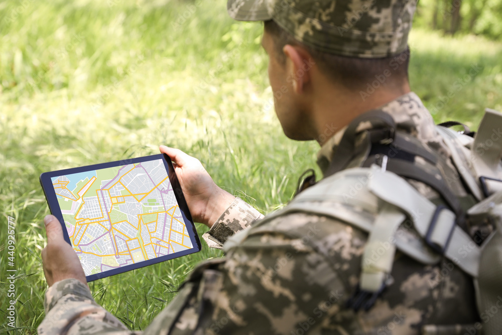 Wall mural Soldier with backpack using tablet in forest