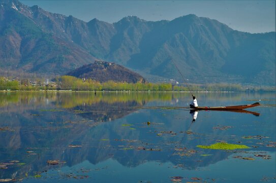 fisherman fishing in lake with mountains © Hammad