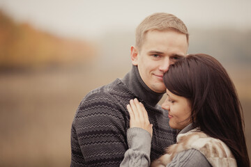 Fototapeta premium couple on autumn walk outdoors. Two lovers are hugging in autumn garden. Love and tender touch. Foggy cloudy day filled with the warmth of love. Beautiful autumn landscape for romantic date. 