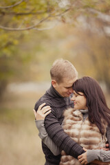 couple on autumn walk outdoors. Two lovers are hugging in autumn garden. Love and tender touch. Foggy cloudy day filled with the warmth of love. Beautiful autumn landscape for romantic date. 