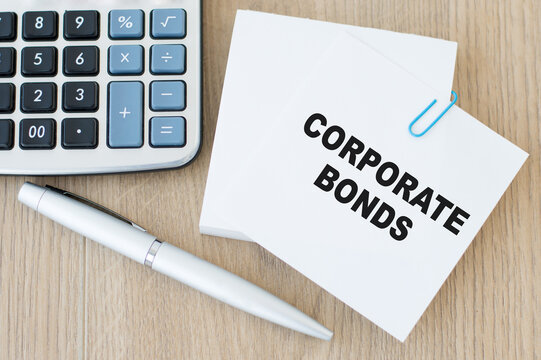 Corporate bonds written on a white business card a calculator and a pen on a wooden background. Financial concept