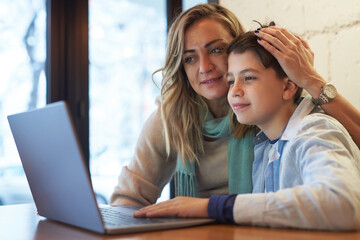 Mom and son doing some computer work together in a cafe