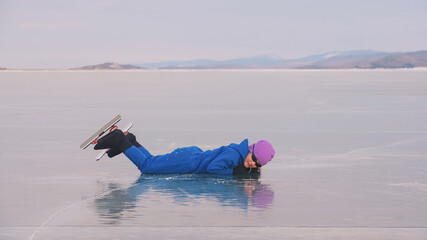 Naklejka premium The child train on ice speed skating. The athlete stretches, warms up, rest. The kid girl skates in winter in sportswear, sport glasses. Children speed skating short long track. Outdoor slow motion.