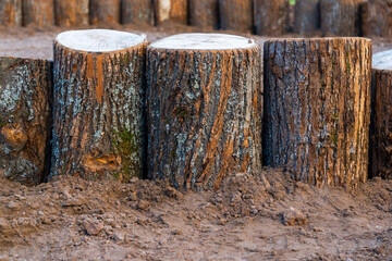 Decorative fence made of wooden stumps. Sandbox fence in the children's playground