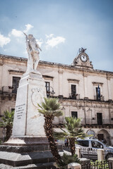 Obraz premium WW2 Memorial with Modica City Hall in the Background, Ragusa, Sicily, Italy, Europe, World Heritage Site