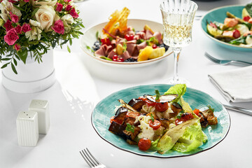 Baked eggplants with cheese, on the table surrounded by other Italian dishes, banquet table, light tablecloths
