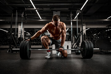 Handsome athlete in good shape preparing the barbell for training, achieving success through...