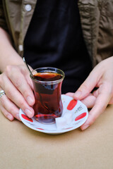 The girl drinks turkish tea in a traditional glass cup on the summer terrace of the restaurant. A cup of aromatic hot tea with a sugar cube. Enjoy the moment, take a break
