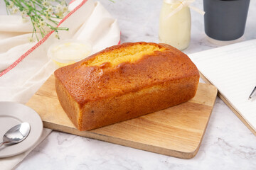Pound cake with lemon glaze on cutting board, milk in glass bottle.