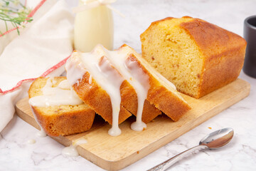 Sliced pound cake topped with lemon glaze on a cutting board and spoon are marble table. - obrazy, fototapety, plakaty