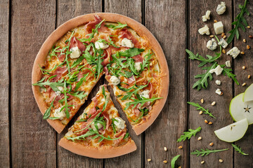 Sliced pizza with prosciutto, gorgonzola, pear, pine nuts, arugula