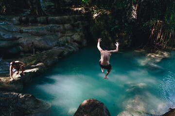 Fototapeta na wymiar Man jumping into a natural pond