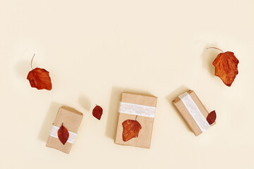 Autumn DIY gift boxes from craft paper decorated red dry leaves on beige,  zero waste holidays.