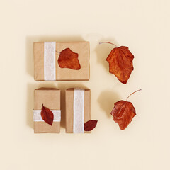 Autumn composition with red autumn leaves and handmade festive presents boxes. Autumnal fall season holiday concept.