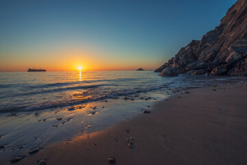 Tropical Sunrise at the beach with the rocks and sea weaves. Sun ways visible thru the rocks. Empty space available.