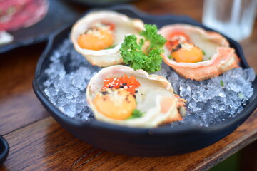 Meat in blak bowl on wood table.