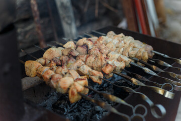 Soft focused shot of marinaded pork meat pieces on skewers frying over bonfire. Kebab or traditional shashlik cooking with lot of smoke.