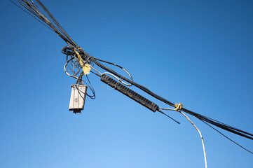 Tangled cables hanging in the street, electricity and telephone