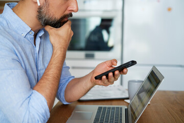 Side view of man holding phone during home office