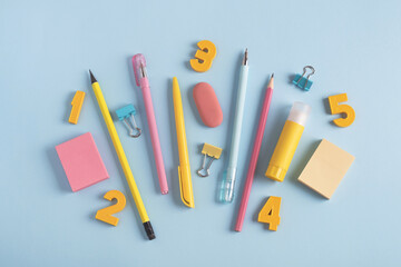 School supplies and numbers on pastel blue background. Back to school concept. Top view, flat lay