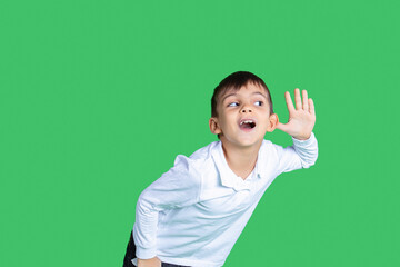 A boy is listening something with an ear. He is paying attention. Listening every word. White shirt is wearing. Green background. 