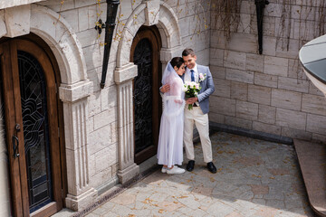 Smiling newlyweds hugging near building outdoors