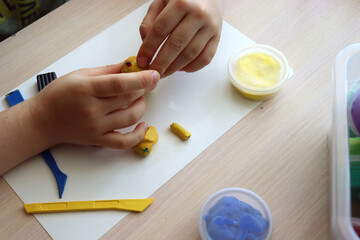 The child plays and builds figures from the play dough. Children's hands with colored plasticine. Development of fine motor skills of fingers in children