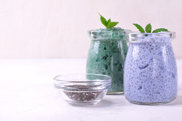 Chia pudding with spirulina and matcha tea powders topped with mint and served in glass jars. Healthy dessert