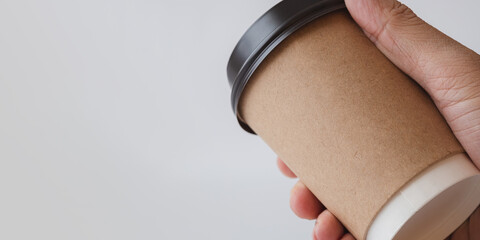 Close up of Man Hand Holding a Recycle Brown Paper Coffee Cup on Gray Background, Mockup Template for Logo Design, Branding, Copy Space for Text.