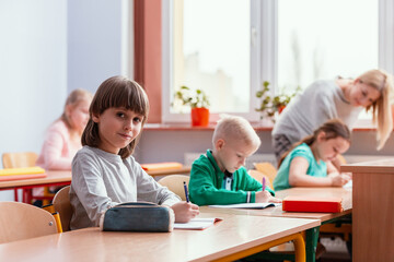 Children sit at the tables in the classroom waiting for the first lesson in the new school year