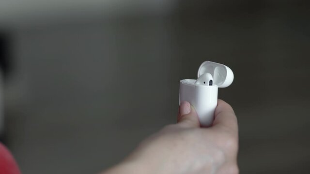 Close up of woman hands holding ear buds charging case and taking one out