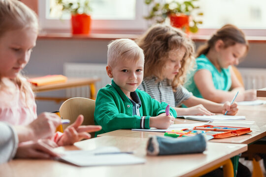 Happy children sit together at the table during the first physics lesson in the new school year