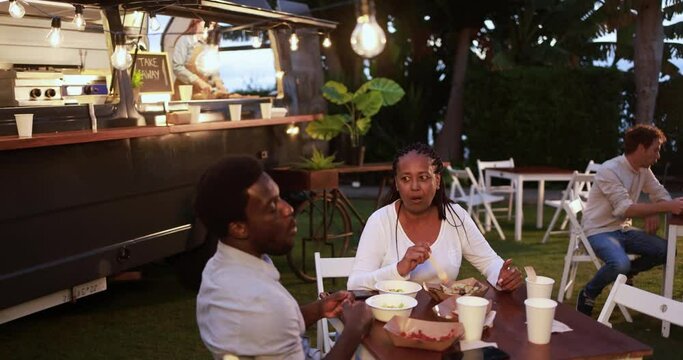 African mother and son eating food truck food dinner outdoor - Family and summer concept