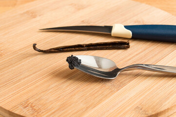 Vanilla on a spoon. A knife and a vanilla stick lie side by side