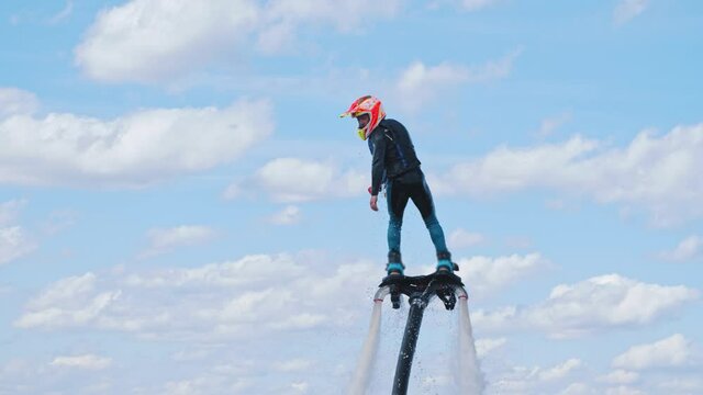 A man moving in the river using a flyboard attached to his feet and going up above the water