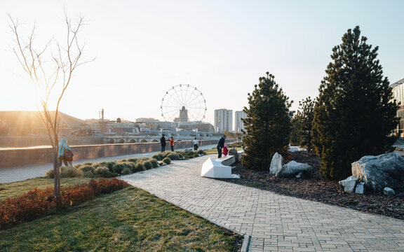 Architectural project near the river Miass in Chelyabinsk. People walking in garden in autumn on sunset