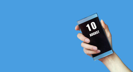 august 10. 10th day of the month, calendar date.Woman's hand holds mobile phone with blank screen on blue isolated background.Summer month, day of the year concept
