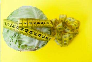 Top view close up of green cabbage with tape measure on yellow background