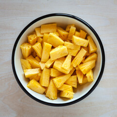 Pineapple chunks top view. Bowl full of fresh tomato cut into pieces.