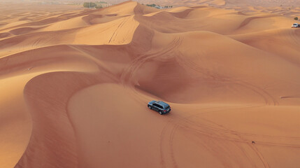 AERIAL. Hight flight above car. Desert safari car sand dunning in the Dubai desert during sunset