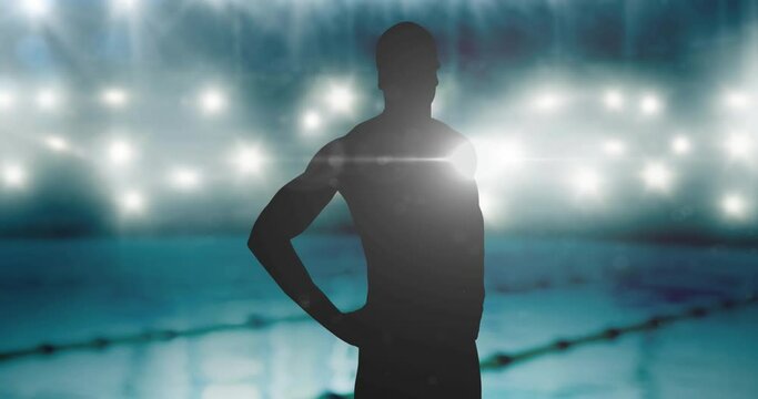 Golden confetti falling over silhouette of male swimmer against swimming pool