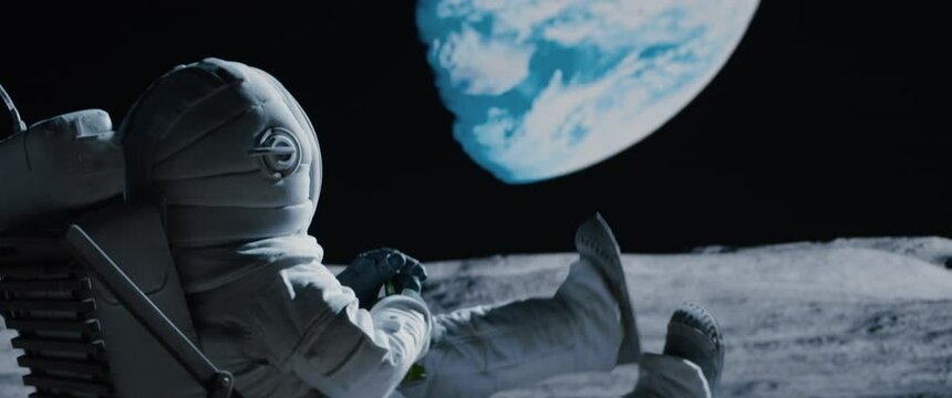 Back view of lunar astronaut having a beer while resting in a beach chair on Moon surface, enjoying view of Earth. Shot with 2x anamorphic lens