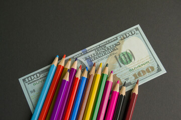 multicolored pencils on souvenir dollar bills. items lie on a black background