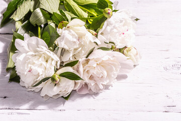 Bouquet of fresh white peonies on white old planks background