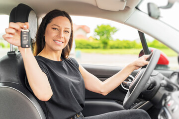 Attractive young woman shows the keys to the car. Beautiful joyful girl in the car.