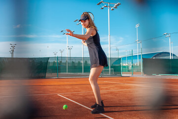 A beautiful woman plays tennis on the court. Sunlight, training, competition. Outdoor sports, team...